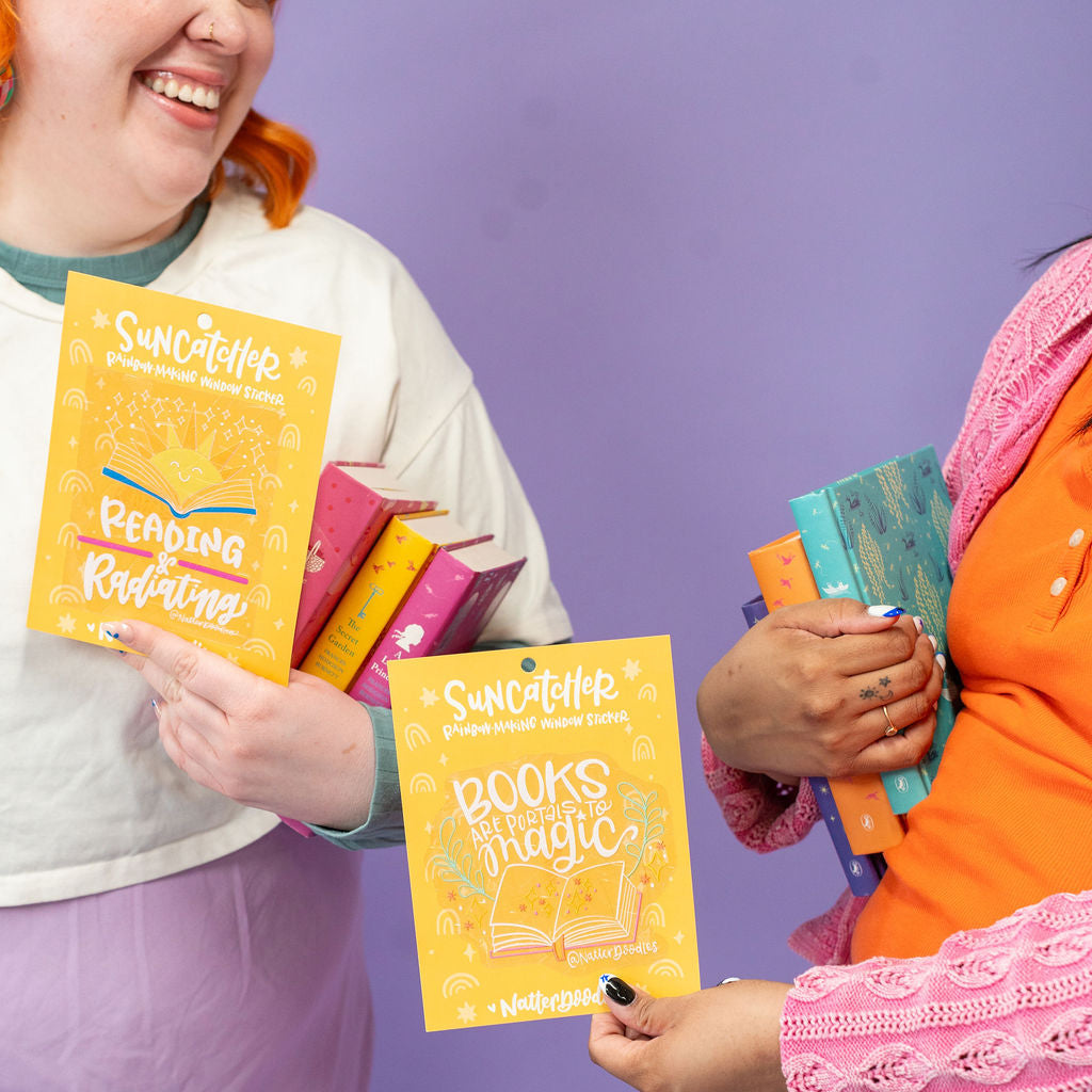 Two people holding colorful suncatchers with a purple background