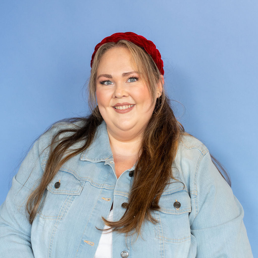 Woman wearing a denim jacket and red headband against a blue background