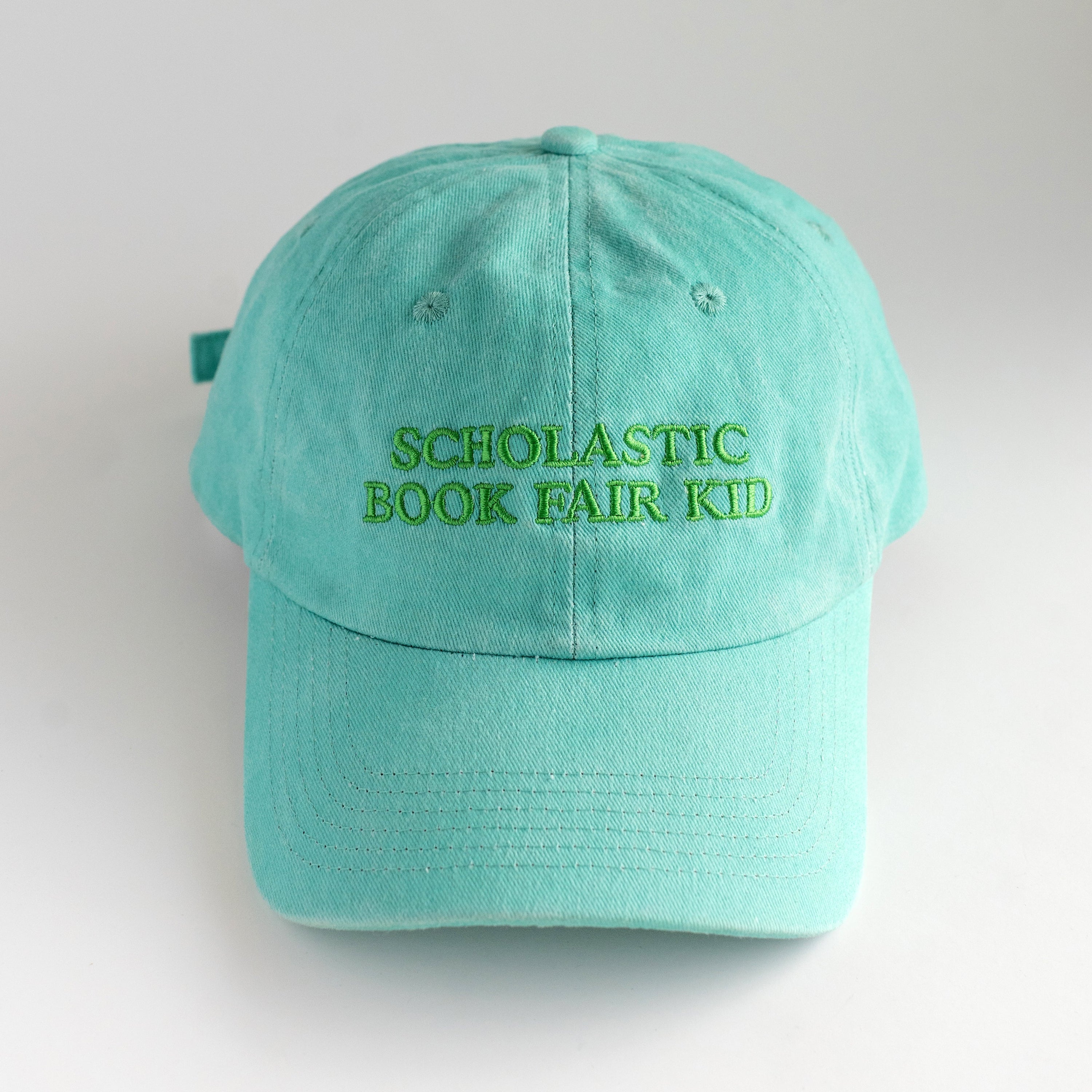 Mint green cap with 'Scholastic Book Fair Kid' text on a light gray background