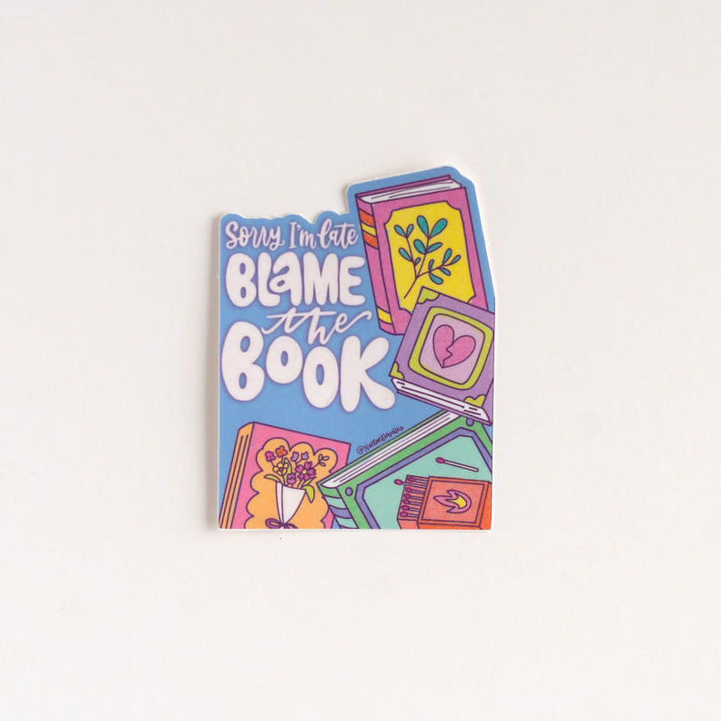 Colorful book titled 'Blame the Book' sticker on a white background