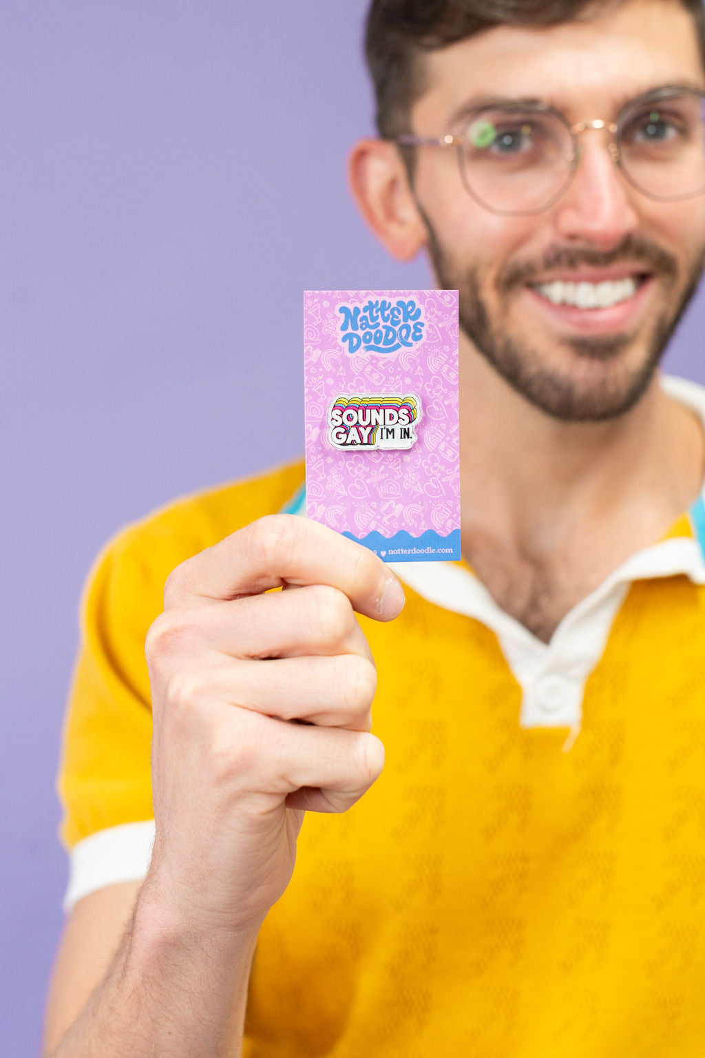 Man holding a pink and blue product packaging against a purple background