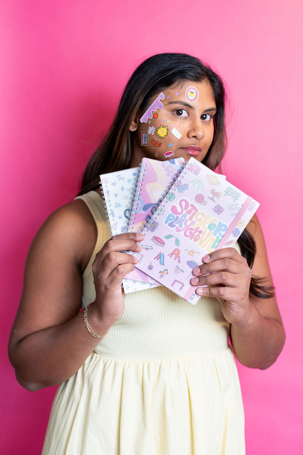 Woman holding colorful stationery items against a pink background