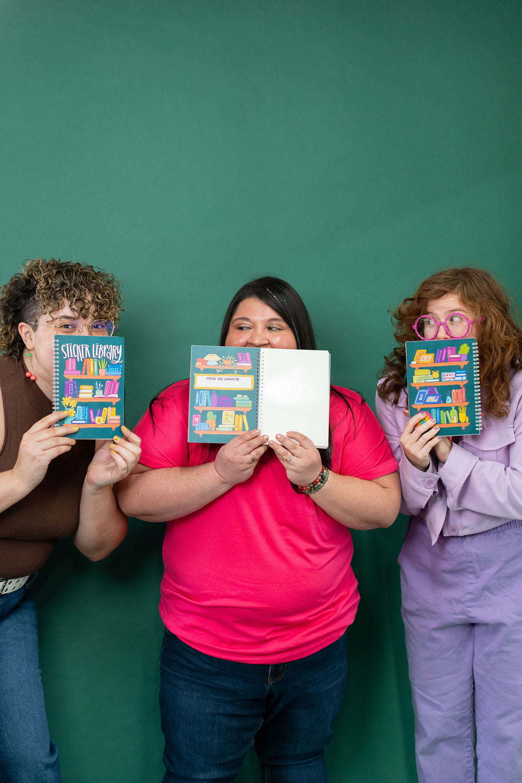 Three people holding colorful books against a green background