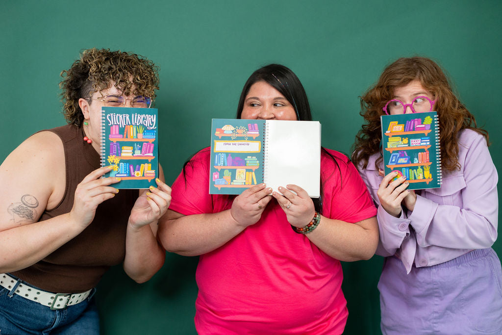 Three people holding colorful sticker books in front of a green background