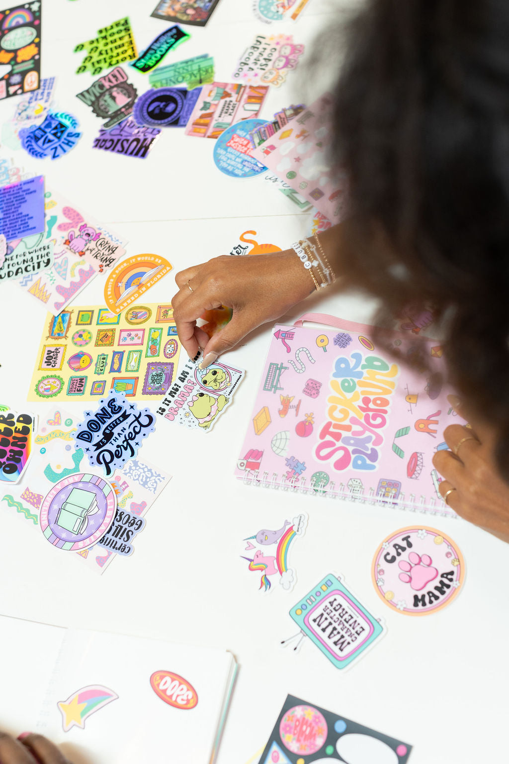 hands arranging colorful stickers on a white surface