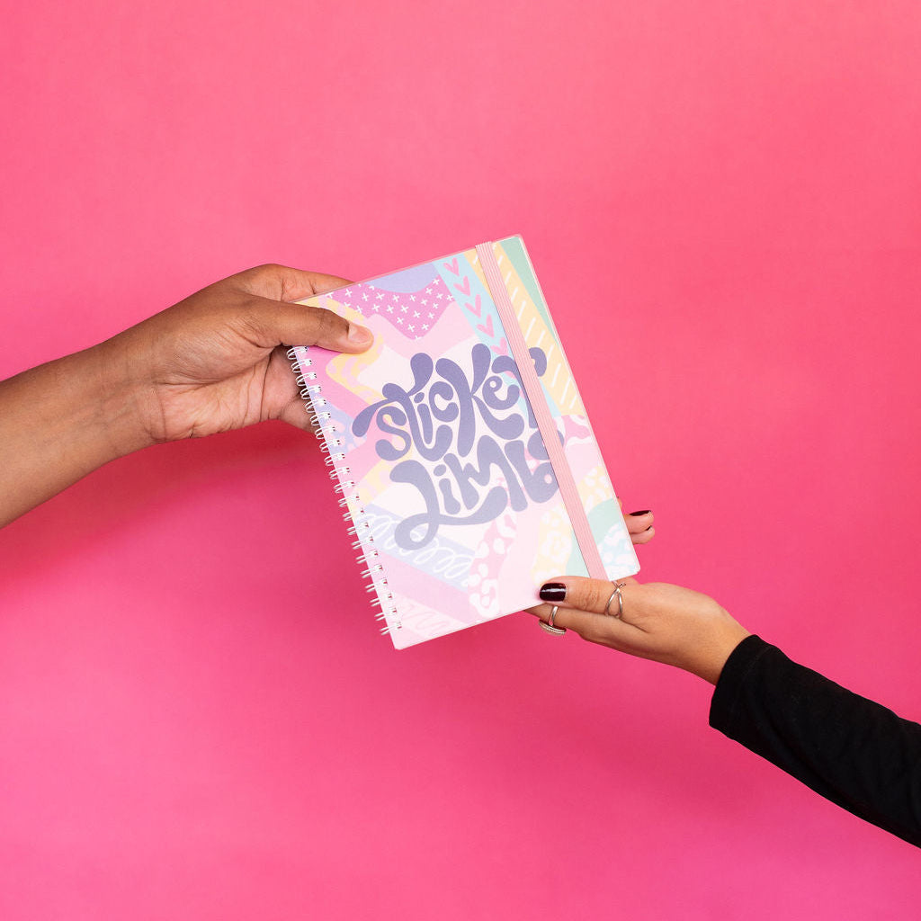 Two hands holding a colorful notebook with 'Squeak Limbo' text against a pink background