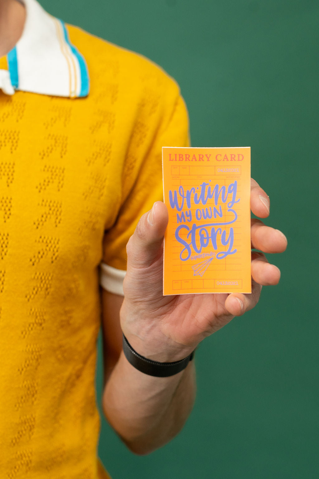 Person holding a card with 'Writing My Own Story' text against a green background