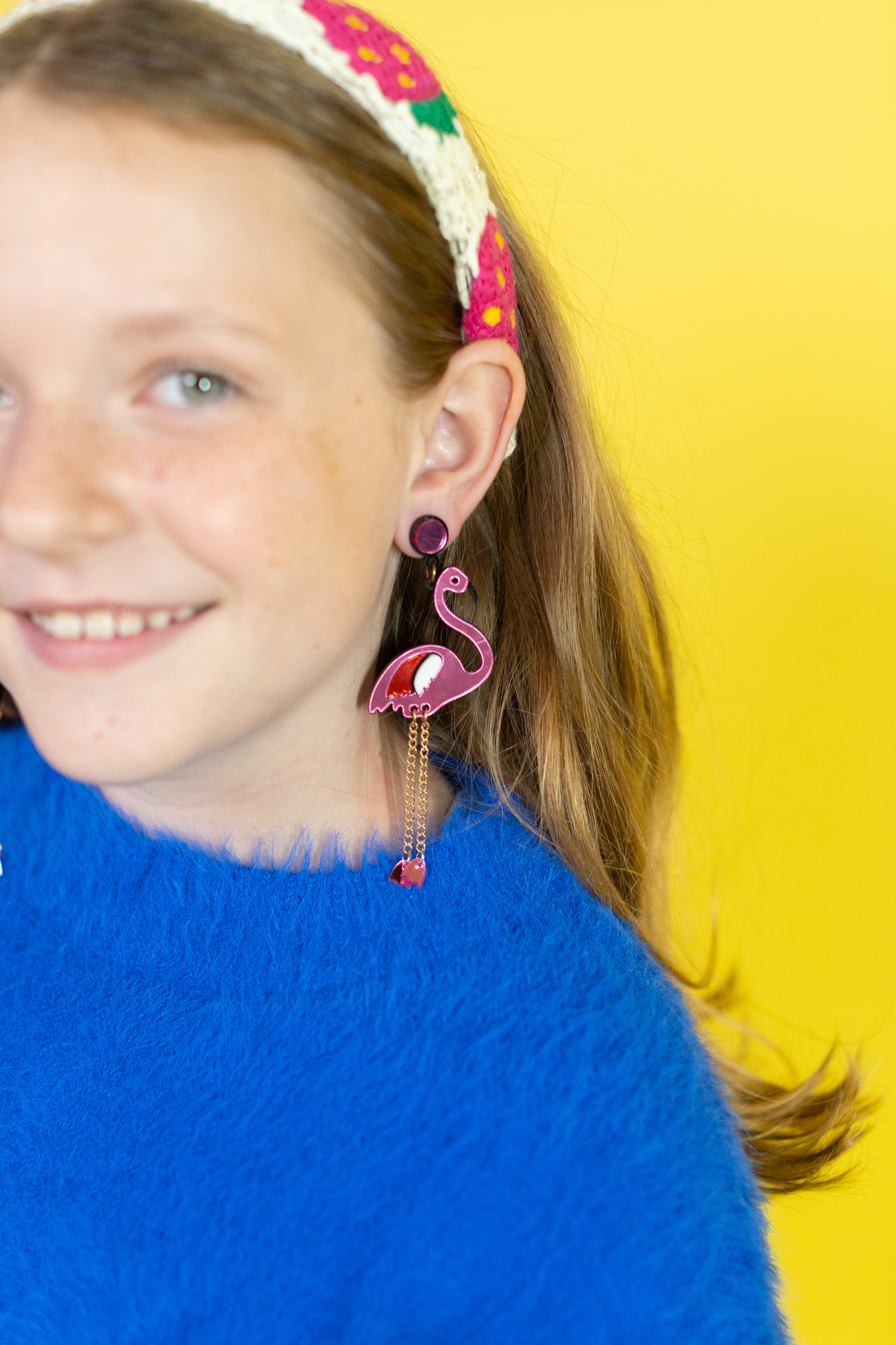 Girl wearing pink flamingo earrings with a yellow background