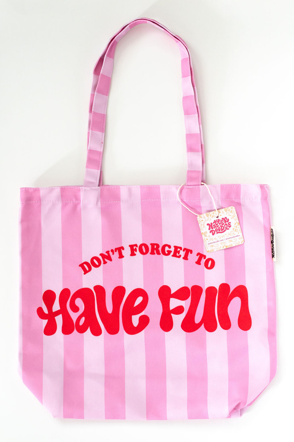 Pink striped tote bag with red text 'DON'T FORGET TO HAVE FUN' on a white background