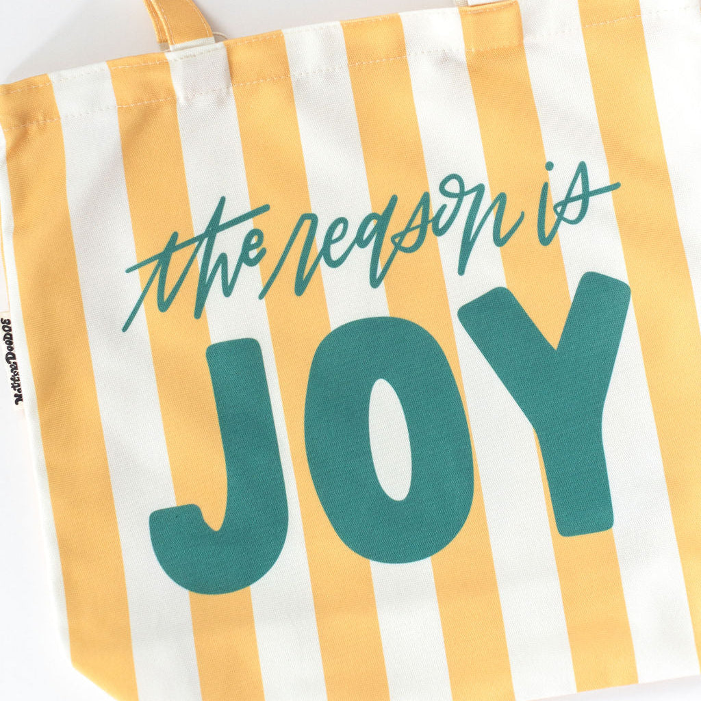 Striped tote bag with 'the reason is JOY' text on a white background