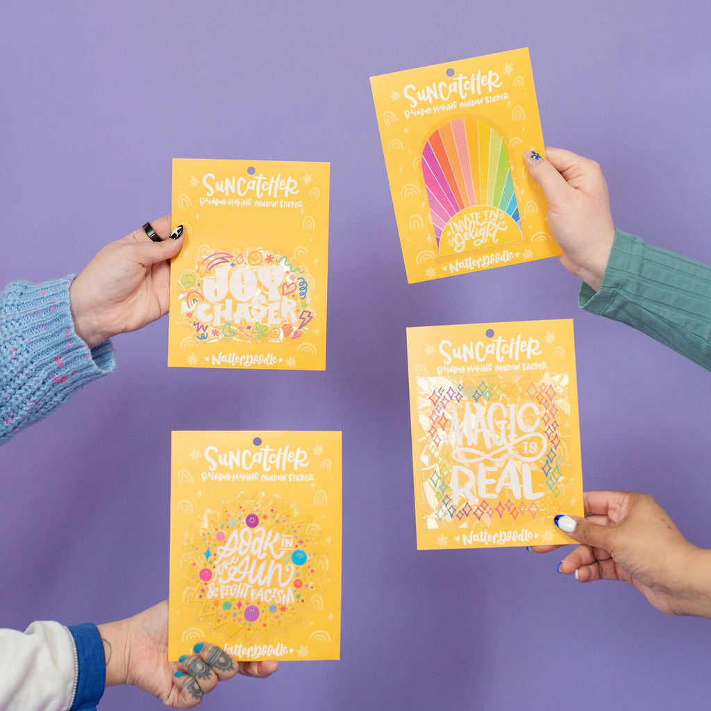 Four hands holding yellow packages with colorful designs against a purple background