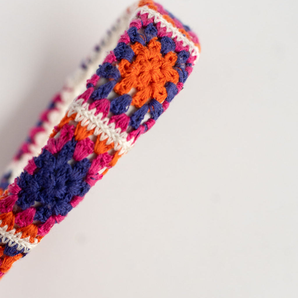 Colorful crocheted headband with a geometric pattern on a light gray background