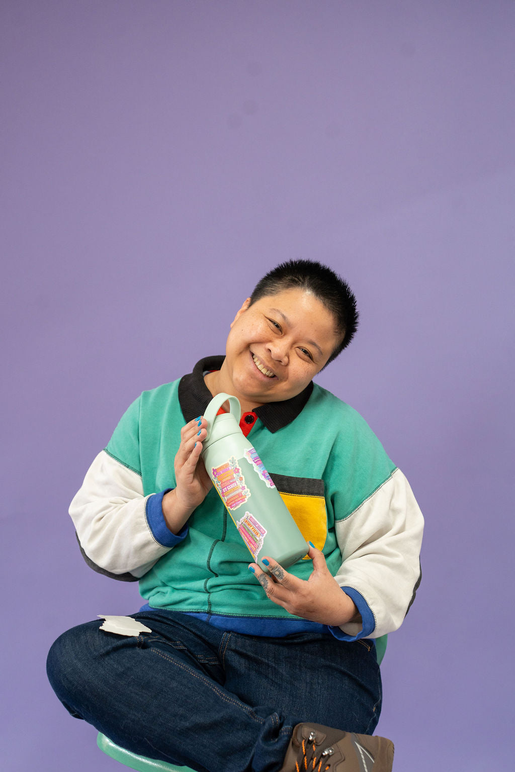 Person holding a bottle with a purple background